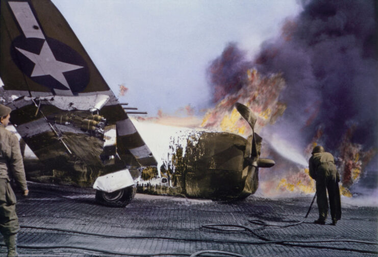 American soldiers standing around a Republic P-47 Thunderbolt that's on fire