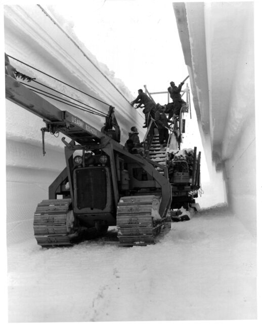 US Army personnel standing atop a large construction vehicle