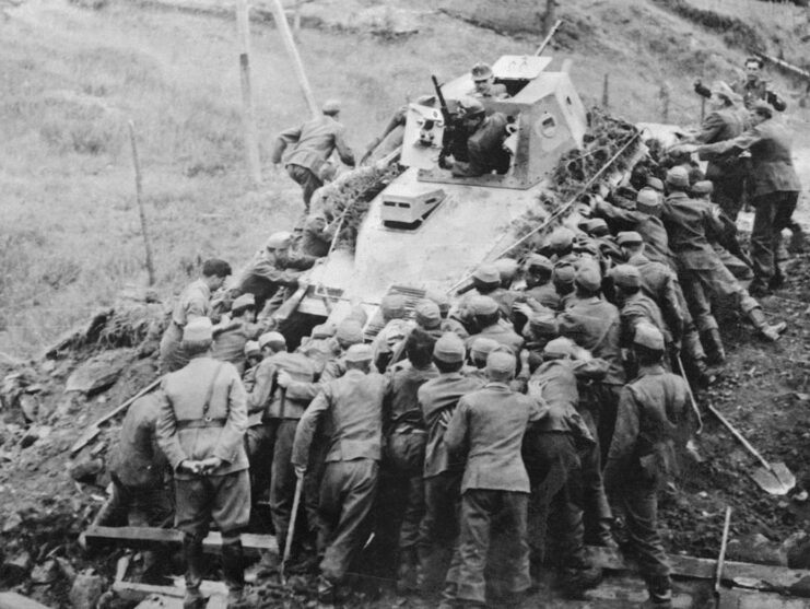 Hungarian soldiers pushing a Soviet tank up an embankment
