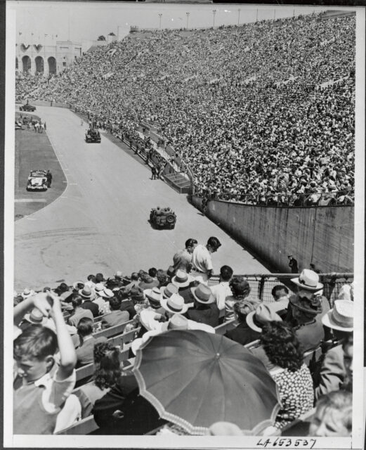 Crowd watching military vehicles drive along the track at the LA Coliseum