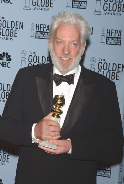 Donald Sutherland posing with his Golden Globe on a red carpet