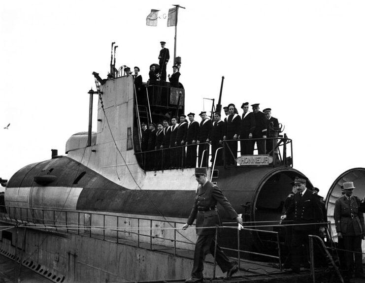 Charles de Gaulle walking away from the French submarine Surcouf while sailors watch on