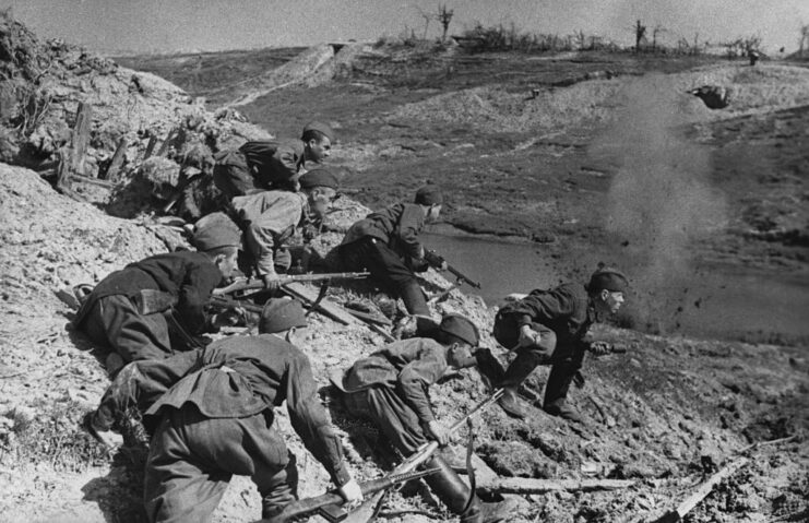 Red Army soldiers crouching on the rocky ledge of a hill
