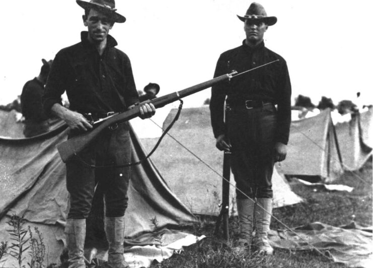 Two soldiers standing with M1903 Springfields at a US military camp