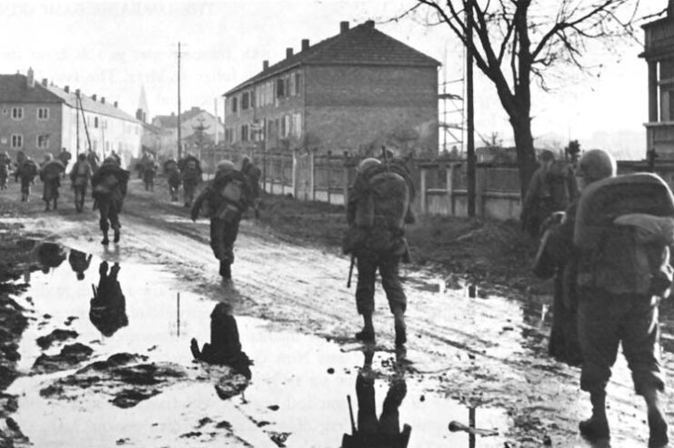 Members of the 5th Infantry Division walking along a muddy street