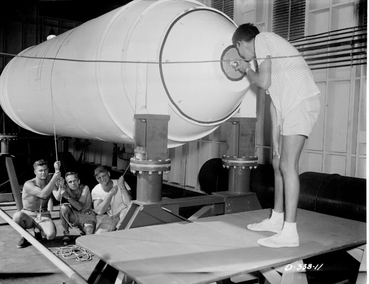 Men standing around and below a nuclear bomb