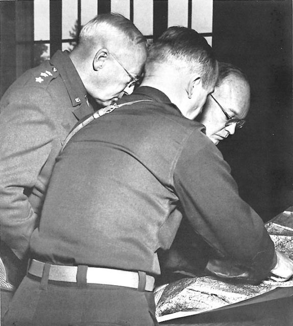 George Patton, Dwight D. Eisenhower and another military official looking at a map spread out on a table