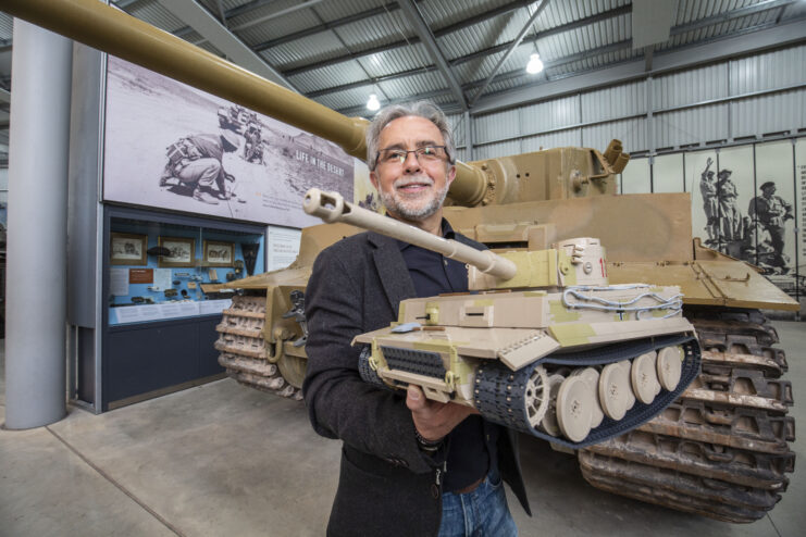 Robert Podleś holding the brick model of the Tiger 131 while standing in front of the real tank