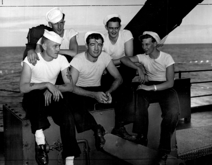 Jack Needham, Donald Head, L.V. Julihn, Kenneth Wilson, Dan Clark, Jack Murry, S.B. Hankins and an unidentified sailor sitting on the deck of a ship