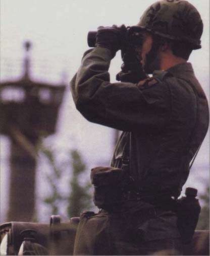Soldier with the 11th Armored Cavalry Regiment looking through a pair of binoculars