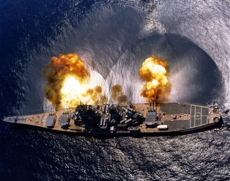 Aerial view of the USS Iowa (BB-61) firing her deck guns at sea