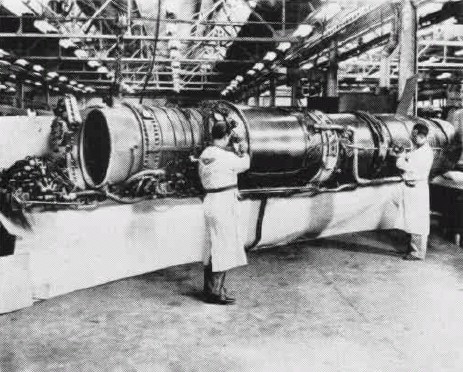 Two workers standing around a Westinghouse J40 engine in a factory