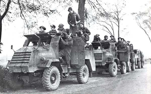 Members of the Royal Hamilton Light Infantry (Wentworth Regiment), 2nd Canadian Infantry Division riding in vehicles along a road