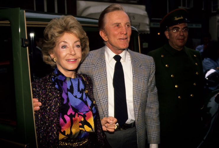 Kirk Douglas walking with his arm around Anne Buydens