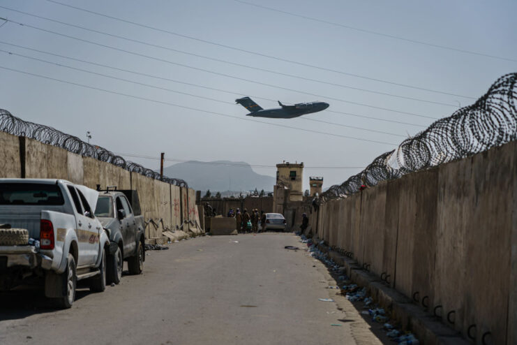 Boeing C-17 Globemaster III flying over walls lined with barbed wire
