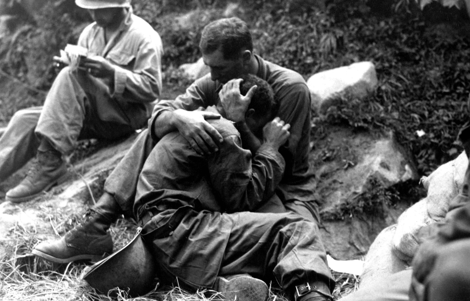 Grieving American GI being comforted by another during the Korean War