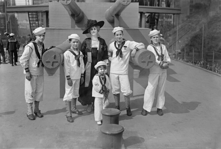 Grace Carley Harriman standing near the USS Recruit's (1917) guns with Junior Naval and Marine Scouts