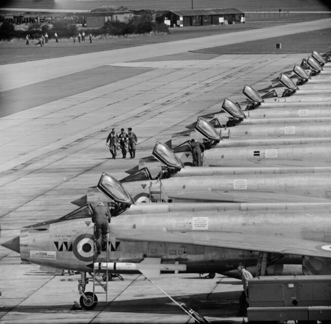Members of No. 74 Squadron RAF walking past a row of English Electric Lightnings