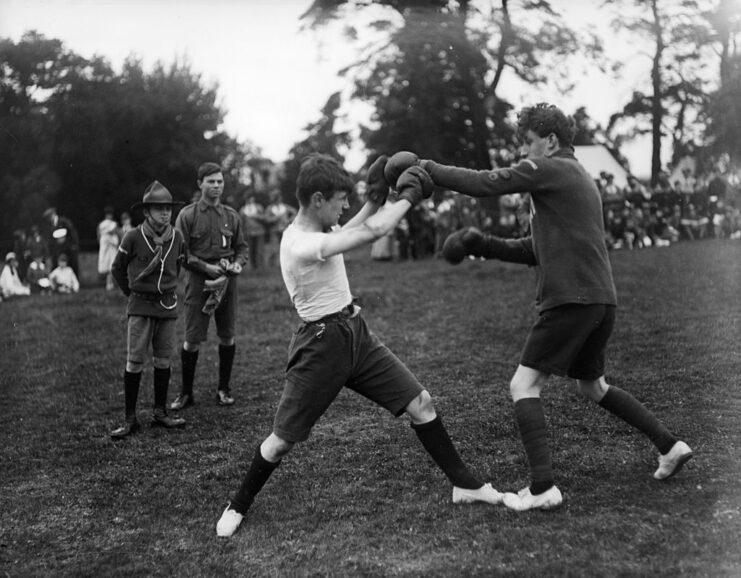 Two Boy Scouts boxing each other while two others watch