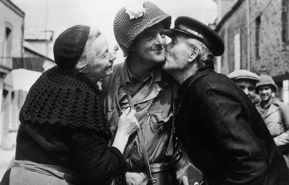 American liberator being kissed on the cheek by an elderly couple