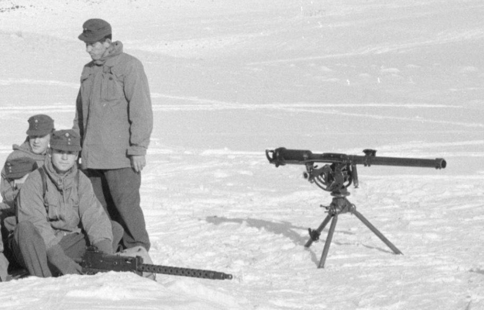 Group of men standing near an M18 recoilless rifle in the snow