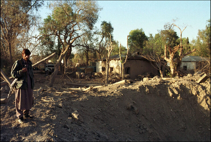 Afghan male standing next to a large crater in the ground