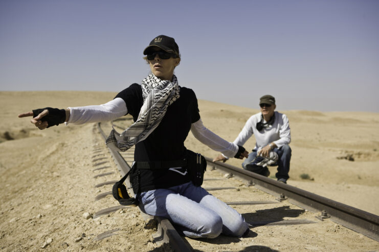 Kathryn Bigelow and an unidentified man sitting at railway tracks in the middle of the desert