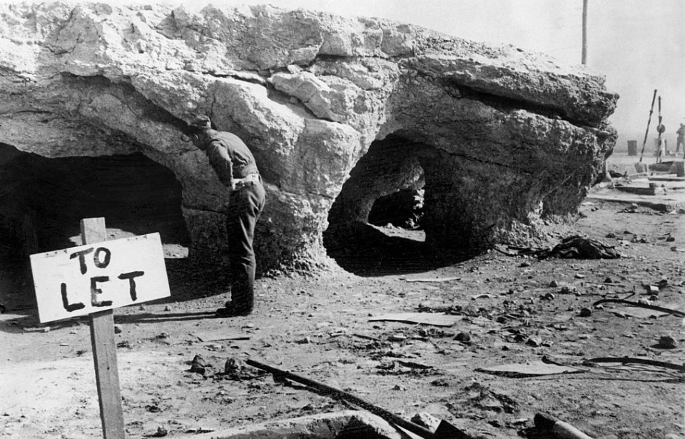 Soldier standing at the entrance of a cave used by the Rats of Tobruk