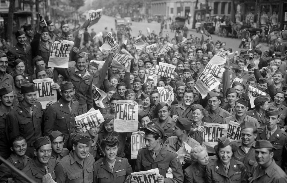 American servicemen and Parisians holding up newspapers in celebration of the Japanese surrender