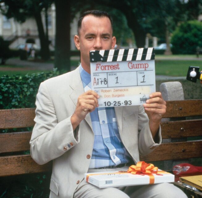 Tom Hanks holding up clapperboard with "Forrest Gump" written on it
