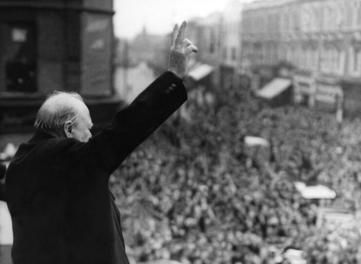 Winston Churchill holding up the "V" for Victory sign in front of a large crowd