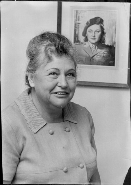 Nancy Wake standing near a portrait of her younger self
