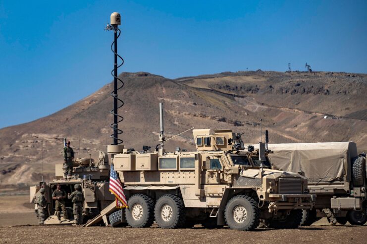 American soldiers standing beside a military vehicle in the Syrian desert