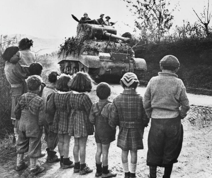 Children watching an M4 Sherman tank drive by