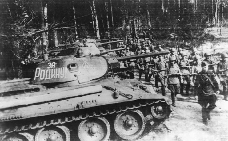 Red Army soldiers marching by a T-34 tank