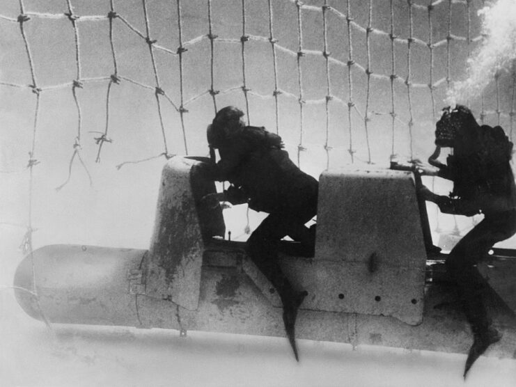 Two Italian frogmen riding a submarine torpedo through underwater netting