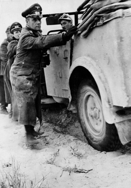Erwin Rommel and other German military personnel pushing a vehicle stuck in the sand