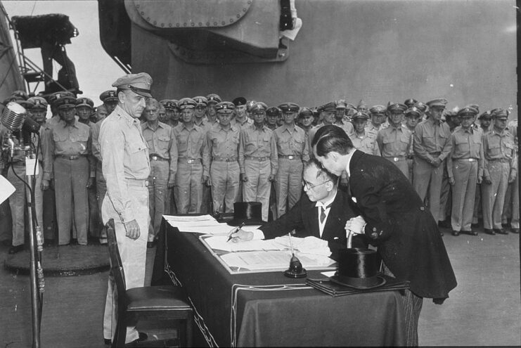 Mamoru Shigemitsu signing the Instrument of Surrender while Allied and Japanese personnel watch on