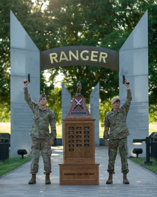 1st Lt. Vince Paikowski and Alastair Keys standing at the entrance to the National Ranger Memorial while aiming pistols into the air