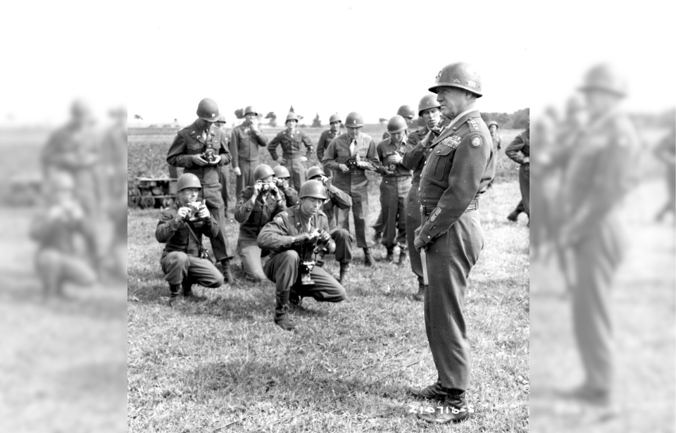 George Patton standing among cameramen from the 103rd Infantry Division