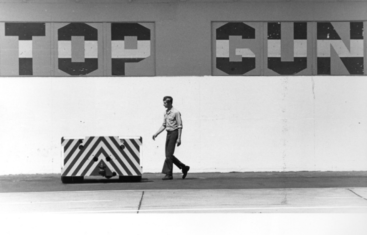 Personnel walking beneath "TOP GUN" painted in large lettering