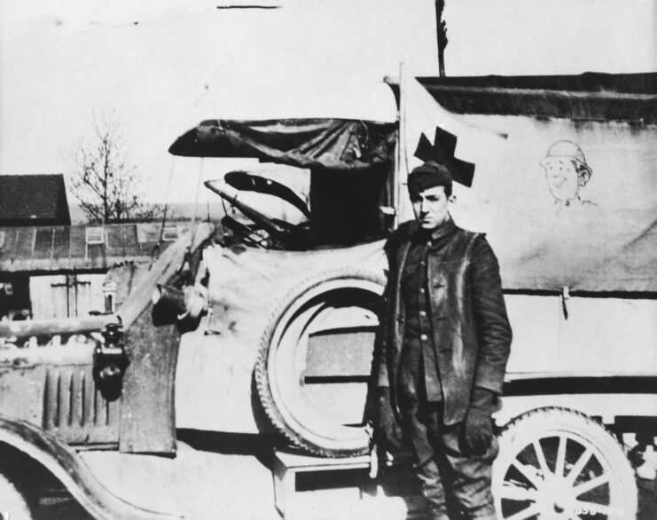 Walt Disney standing with a Ford Model T ambulance