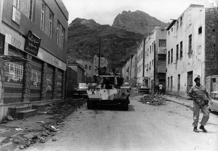 British soldier and tank moving along a street