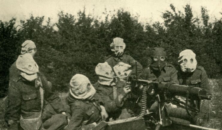 Group of British machine gunners wearing gas masks in the field