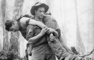 Leslie "Bull" Allen carrying an injured American soldier through the jungle