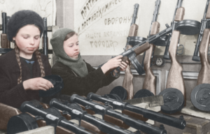 Two children assembling submachine guns at a table