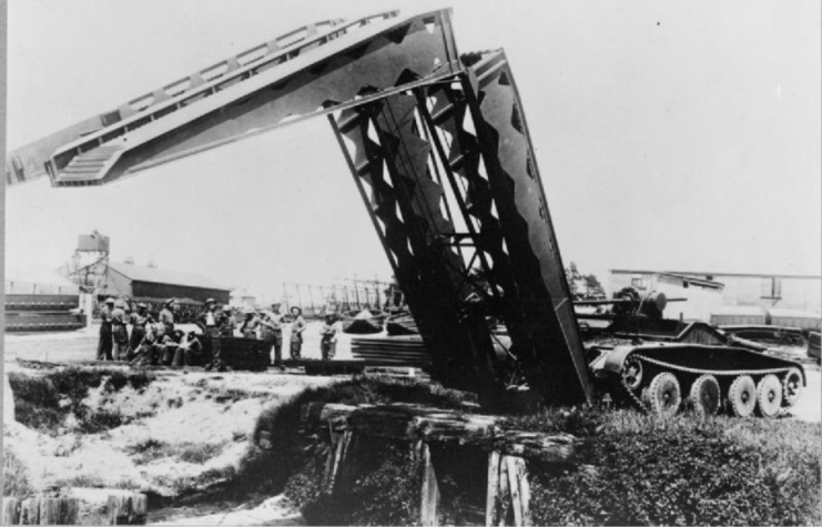 Covenanter Bridgelayer parked along the edge of a narrow chasm while troops stand nearby