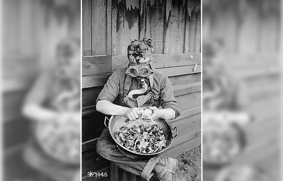 Soldier peeling onions while wearing a gas mask