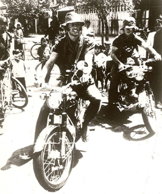 Sean Flynn and Dana Stone sitting on motorcycles while others stand nearby