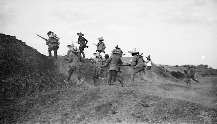 Armed Mexican revolutionaries running up a hill